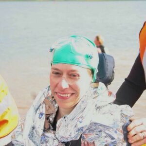 Headshot of Caroline, in a wheelchair wearing a space blanket and a green swimming hat